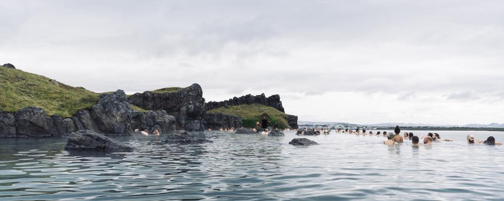Sky Lagoon på Island. Turister som njuter av ett geotermiskt spa med uppvärmt vatten under en kall dag. Av: Renata Tyburczy