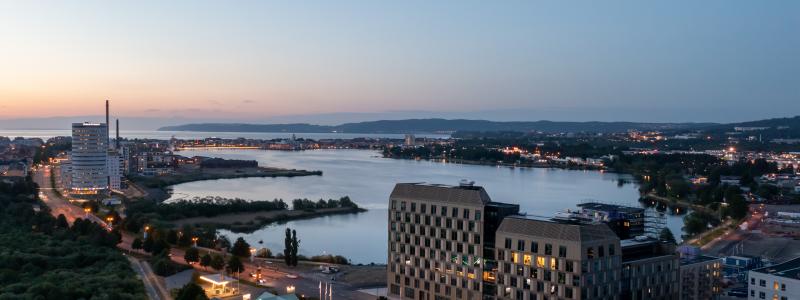 Kvällsvy över det nio våningar höga kontorshuset med Munksjön och Vättern i bakgrunden. Bild: Skanska