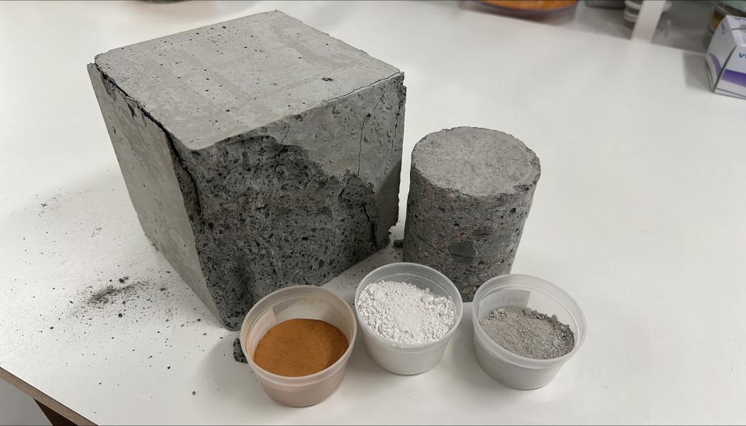 Olika typer av bindemedel: lera, slagg och cement intill en betongkub som har testats för tryckhållfasthet. Foto: RISE