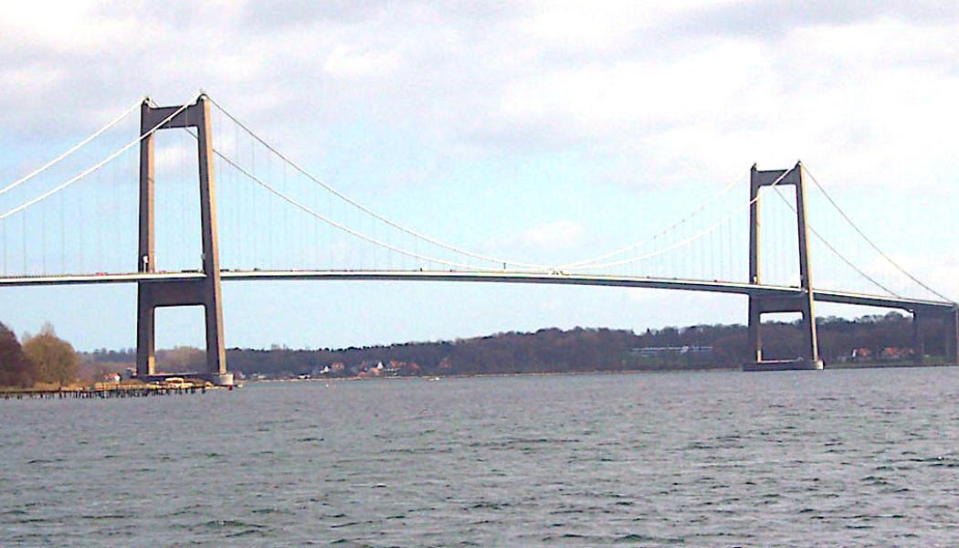 Det finns två broar i Danmark som heter Lilla Bältbron. Det är en äldre från 1935 och en nyare från 1970 (i bilden). Båda broarna går över Lilla Bält mellan Snoghøj (numera en del av Fredericias tätort) på Jylland och Middelfart på Fyn. Den nyare bron är en ren vägbro och vägen utgörs av en viktig motorväg. Foto: Wikipedia Commons. Kredit: Kredit:  Ävar Arnfjöro Bjarmason.
