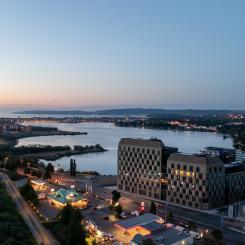 Kvällsvy över det nio våningar höga kontorshuset med Munksjön och Vättern i bakgrunden. Bild: Skanska