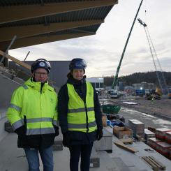 Projektledarna Anders Emilsson och Cecilia Wahlskog på den Östra läktaren av Rimnersvallen, i bakgrunden syns det första belysningstornet komma på plats. Foto: Uddevalla kommun