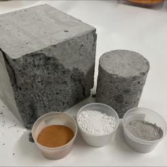 Olika typer av bindemedel: lera, slagg och cement intill en betongkub som har testats för tryckhållfasthet. Foto: RISE